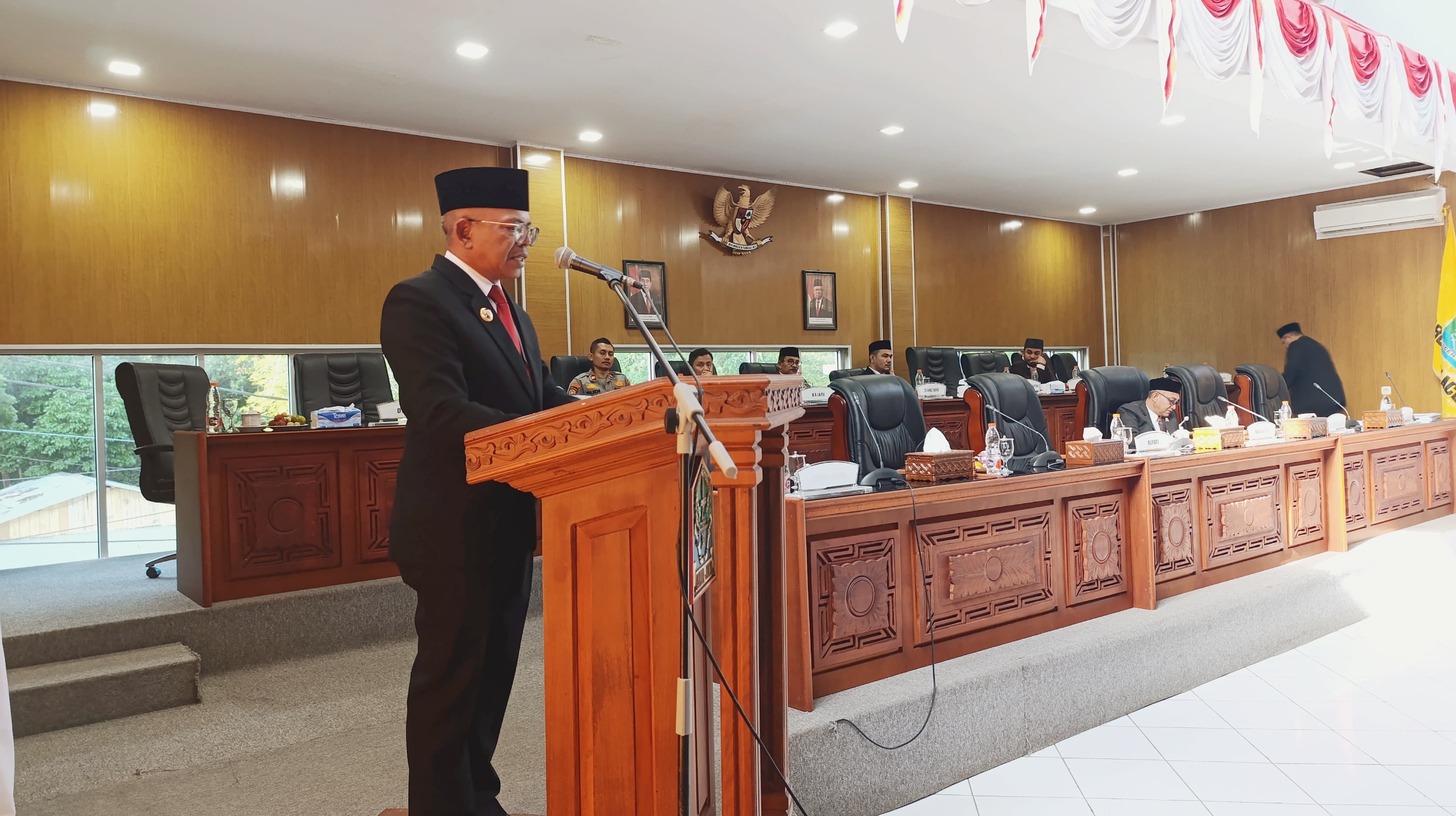 Rapat Paripurna merupakan salah satu agenda penting dalam pemerintahan daerah, terutama dalam konteks pengelolaan keuangan dan perencanaan pembangunan. Pada kesempatan kali ini, Pj. Bupati Aceh Jaya turut hadir untuk membahas berbagai hal krusial yang berkaitan dengan pertanggungjawaban Anggaran Pendapatan dan Belanja Kabupaten (APBK), Rencana Pembangunan Jangka Panjang (RPJP), serta perubahan Kebijakan Umum Anggaran dan Prioritas Plafon Anggaran Sementara (KUA-PPAS) 2024. Melalui rapat ini, diharapkan dapat tercipta transparansi dan akuntabilitas dalam pengelolaan keuangan daerah, serta meningkatkan partisipasi masyarakat dalam proses pembangunan. Pembahasan ini tidak hanya berfokus pada angka dan perencanaan, tetapi juga pada dampak yang akan dirasakan oleh masyarakat Aceh Jaya ke depan. Pertanggungjawaban APBK: Transparansi dan Akuntabilitas Keuangan Daerah Pertanggungjawaban APBK merupakan salah satu aspek penting dalam pengelolaan keuangan daerah. Dalam rapat paripurna yang dihadiri oleh Pj. Bupati Aceh Jaya, berbagai elemen pengelolaan keuangan dibahas secara mendalam. Pertanggungjawaban APBK mencakup laporan realisasi anggaran yang menunjukkan bagaimana dana publik digunakan selama satu tahun anggaran. Hal ini penting untuk menjamin transparansi dan akuntabilitas, sehingga masyarakat dapat mengetahui alokasi dan penggunaan dana yang dihasilkan dari pajak dan sumber pendapatan lainnya. Dalam konteks Aceh Jaya, laporan pertanggungjawaban ini meliputi berbagai program dan kegiatan yang telah dilaksanakan. Misalnya, pembangunan infrastruktur, kesehatan, pendidikan, dan bantuan sosial. Setiap program diharapkan dapat memberikan dampak positif bagi masyarakat. Selain itu, Pj. Bupati juga menekankan pentingnya evaluasi terhadap program-program yang telah berjalan untuk mengetahui efektivitas dan efisiensinya. Dengan demikian, setiap pengeluaran anggaran harus dapat dipertanggungjawabkan dan memberikan manfaat maksimal bagi masyarakat. Rapat ini juga menjadi forum bagi anggota dewan untuk menyampaikan masukan dan pertanyaan terkait dengan laporan tersebut. Partisipasi aktif dari anggota dewan menunjukkan adanya pengawasan yang baik terhadap pengelolaan keuangan daerah. Hal ini penting untuk menciptakan iklim pemerintahan yang sehat, di mana semua pihak memiliki peran dalam pengawasan dan pengelolaan anggaran. Dalam pertanggungjawaban APBK, juga dibahas mengenai sisa anggaran yang tidak terpakai dan bagaimana cara pemanfaatannya. Sisa anggaran ini bisa digunakan untuk program-program prioritas yang mendesak yang belum teranggarkan atau untuk menutup kekurangan di sektor-sektor tertentu. Dengan demikian, rapat paripurna ini tidak hanya menjadi ajang laporan, tetapi juga sebagai forum untuk merencanakan langkah-langkah strategis ke depan. RPJP: Rencana Pembangunan Jangka Panjang sebagai Landasan Strategis Rencana Pembangunan Jangka Panjang (RPJP) merupakan dokumen penting yang memandu arah kebijakan dan pembangunan daerah dalam jangka panjang. Dalam rapat paripurna tersebut, Pj. Bupati Aceh Jaya menjelaskan berbagai aspek yang terkandung dalam RPJP, termasuk visi, misi, dan tujuan pembangunan daerah. RPJP ini dirumuskan untuk periode tertentu, biasanya hingga 20 tahun ke depan, dengan mempertimbangkan potensi, tantangan, dan kebutuhan masyarakat. RPJP berfungsi sebagai landasan bagi penyusunan rencana pembangunan tahunan dan rencana kerja pemerintah daerah. Melalui RPJP, pemerintah daerah dapat menetapkan prioritas pembangunan yang harus dilakukan, serta sumber daya yang dibutuhkan untuk mencapai tujuan tersebut. Dalam konteks Aceh Jaya, RPJP diharapkan dapat menciptakan pertumbuhan ekonomi yang inklusif dan berkelanjutan, serta mengurangi kesenjangan sosial di masyarakat. Pj. Bupati juga menekankan pentingnya keterlibatan masyarakat dalam penyusunan RPJP. Dengan melibatkan masyarakat, diharapkan rencana pembangunan yang dihasilkan lebih relevan dan sesuai dengan kebutuhan mereka. Selain itu, partisipasi masyarakat juga dapat meningkatkan rasa memiliki terhadap program-program pembangunan yang dilakukan oleh pemerintah. Dalam rapat tersebut, Pj. Bupati memaparkan pencapaian yang telah berhasil diraih berdasarkan RPJP yang telah ditetapkan sebelumnya. Pencapaian ini meliputi berbagai sektor, seperti infrastruktur, pendidikan, kesehatan, dan pemberdayaan masyarakat. Meskipun demikian, masih banyak tantangan yang harus dihadapi, seperti peningkatan kualitas sumber daya manusia dan pengembangan ekonomi lokal. Oleh karena itu, RPJP harus terus diperbarui dan disesuaikan dengan dinamika yang terjadi di masyarakat. Perubahan KUA-PPAS 2024: Responsif Terhadap Dinamika Kebutuhan Masyarakat Kebijakan Umum Anggaran dan Prioritas Plafon Anggaran Sementara (KUA-PPAS) merupakan dokumen yang mengatur alokasi anggaran pada tahun anggaran yang akan datang. Dalam rapat paripurna kali ini, perubahan KUA-PPAS 2024 menjadi salah satu agenda penting yang dibahas. Perubahan ini diperlukan untuk menyesuaikan alokasi anggaran dengan kebutuhan masyarakat yang terus berkembang, terutama di tengah situasi sosial dan ekonomi yang dinamis. Pj. Bupati Aceh Jaya menyampaikan bahwa perubahan KUA-PPAS 2024 dilakukan dengan mempertimbangkan masukan dari berbagai pihak, termasuk masyarakat dan anggota dewan. Hal ini bertujuan agar anggaran yang dialokasikan benar-benar tepat sasaran dan memberikan manfaat yang maksimal bagi masyarakat. Selain itu, perubahan KUA-PPAS juga perlu dilakukan untuk mengakomodasi program-program prioritas yang muncul sebagai respons terhadap kebutuhan mendesak di masyarakat. Dalam rapat ini, dijelaskan pula mengenai berbagai sektor yang menjadi prioritas dalam perubahan KUA-PPAS 2024. Beberapa sektor yang mendapatkan perhatian khusus antara lain kesehatan, pendidikan, infrastruktur, dan pemberdayaan ekonomi masyarakat. Pj. Bupati berharap, dengan adanya perubahan ini, akan ada peningkatan dalam kualitas pelayanan publik dan kesejahteraan masyarakat. Proses pengesahan perubahan KUA-PPAS juga melibatkan berbagai tahapan, mulai dari pengajuan proposal oleh pemerintah daerah, pembahasan dengan DPRD, hingga penetapan anggaran. Oleh karena itu, penting bagi seluruh pihak untuk berkolaborasi dan bekerja sama dalam proses ini agar tujuan pembangunan dapat tercapai dengan baik. Peran Pj. Bupati dalam Mendorong Partisipasi Masyarakat dan Kualitas Pengelolaan Anggaran Sebagai pimpinan daerah, Pj. Bupati Aceh Jaya memiliki peran strategis dalam mendorong partisipasi masyarakat dalam proses perencanaan dan pengelolaan anggaran. Dalam rapat paripurna, Pj. Bupati menekankan pentingnya komunikasi yang efektif antara pemerintah daerah dan masyarakat. Melalui komunikasi yang baik, masyarakat dapat menyampaikan aspirasi dan kebutuhan mereka yang dapat menjadi masukan dalam penyusunan anggaran. Pj. Bupati juga mendorong transparansi dalam pengelolaan keuangan daerah. Dengan memberikan akses informasi yang jelas dan terbuka kepada masyarakat, diharapkan masyarakat dapat lebih memahami bagaimana anggaran diolah dan digunakan. Ini juga akan menciptakan kepercayaan masyarakat terhadap pemerintah daerah. Selain itu, Pj. Bupati mengajak semua pihak untuk berperan aktif dalam pengawasan anggaran. Pengawasan yang baik akan memastikan setiap dana yang dikeluarkan dapat dipertanggungjawabkan dan digunakan sesuai dengan peruntukannya. Dalam konteks ini, partisipasi masyarakat dalam melaksanakan pengawasan akan sangat berharga untuk menciptakan pemerintahan yang bersih dan akuntabel. Pj. Bupati Aceh Jaya juga menekankan pentingnya peningkatan kapasitas sumber daya manusia di lingkungan pemerintahan daerah. Pelatihan dan pendidikan bagi aparatur sipil negara (ASN) perlu dilakukan agar mereka memiliki pengetahuan dan keterampilan yang memadai dalam mengelola anggaran. Dengan demikian, kualitas pengelolaan anggaran dapat meningkat dan berdampak positif pada pembangunan daerah.